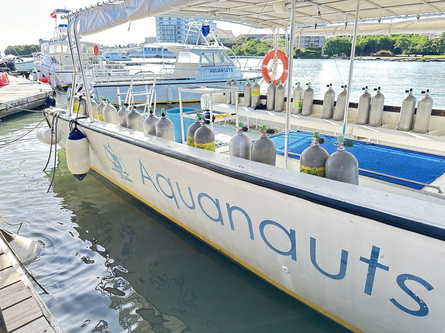 The Aquanauts Grenada dive boat docked at True Blue Bay with scuba tanks lined up and ready for a morning dive.