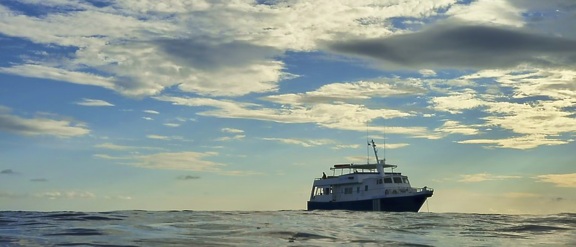 Bahamas Aggressor liveaboard boat on the ocean surface beneath a dramatic cloudy sky in the Bahamas