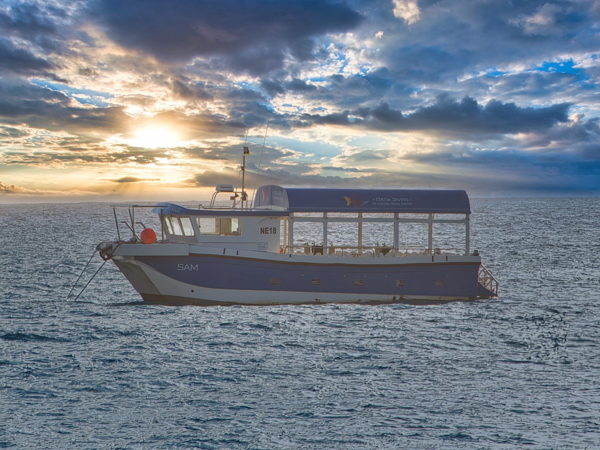 Statia Divers dive boat 'Sam' from Golden Rock Resort on the water during a dramatic sunset in St. Eustatius.